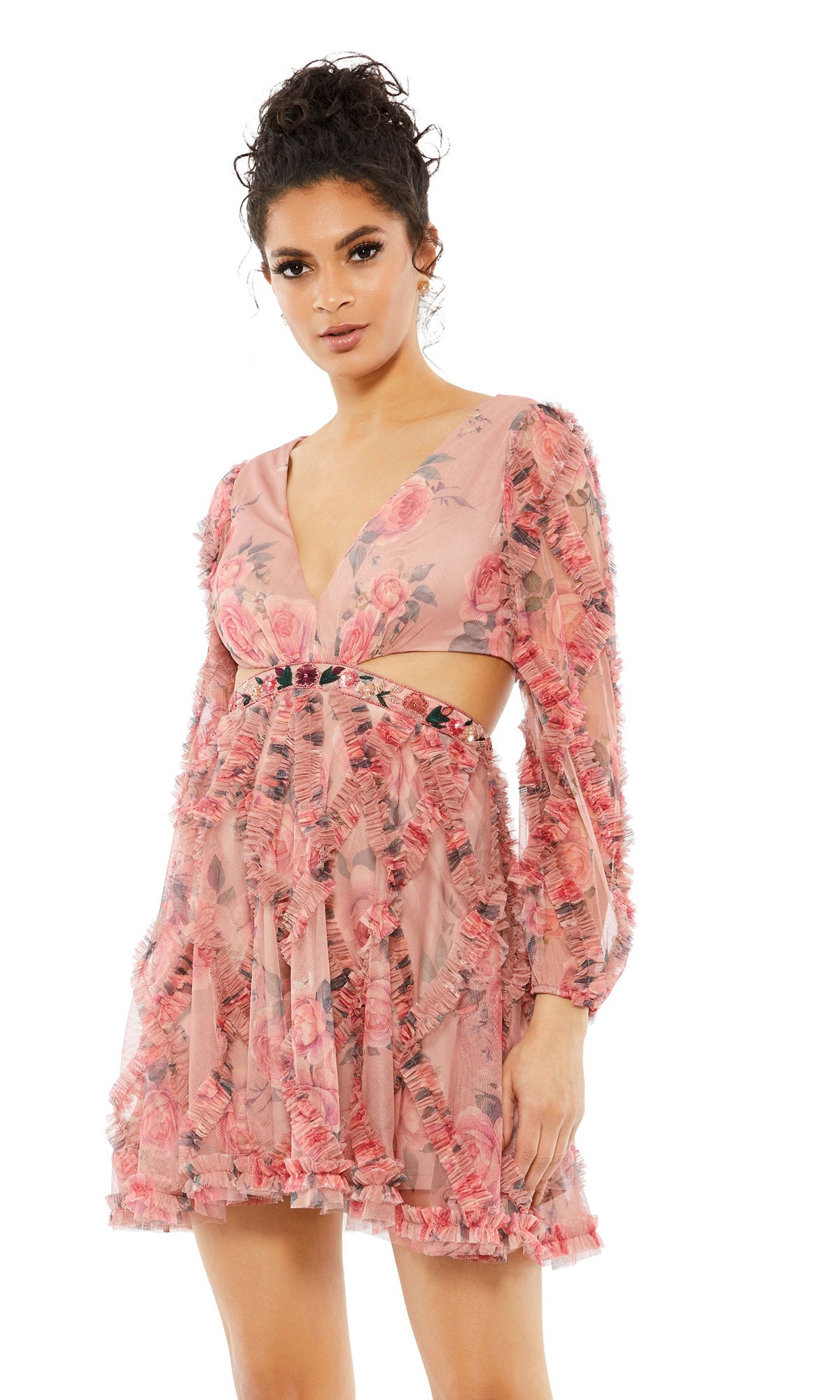 A woman poses in the Long Sleeve Floral-Print Short Party Dress 9151 by Mac Duggal, featuring pink floral prints, long sleeves, sheer detailing, and a deep V-neckline against a plain white background.